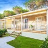 Una casa prefabbricata con terrazza, circondata da alberi e prato verde.