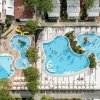 Immagine dall'alto di piscine con scivoli, lettini e ombrelloni, vista dettagliata del complesso.