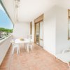 Balcone con tavolo bianco, sedie e lettino, vista esterna.