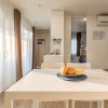 Tavolo bianco con pane, cucina moderna, aria condizionata, e uscita su patio soleggiato.