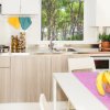 Cucina moderna con frutta sul tavolo e vista sul giardino alberato.