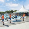 Animatori in uniforme arancione ed esercizi di ginnastica a bordo piscina affollata.